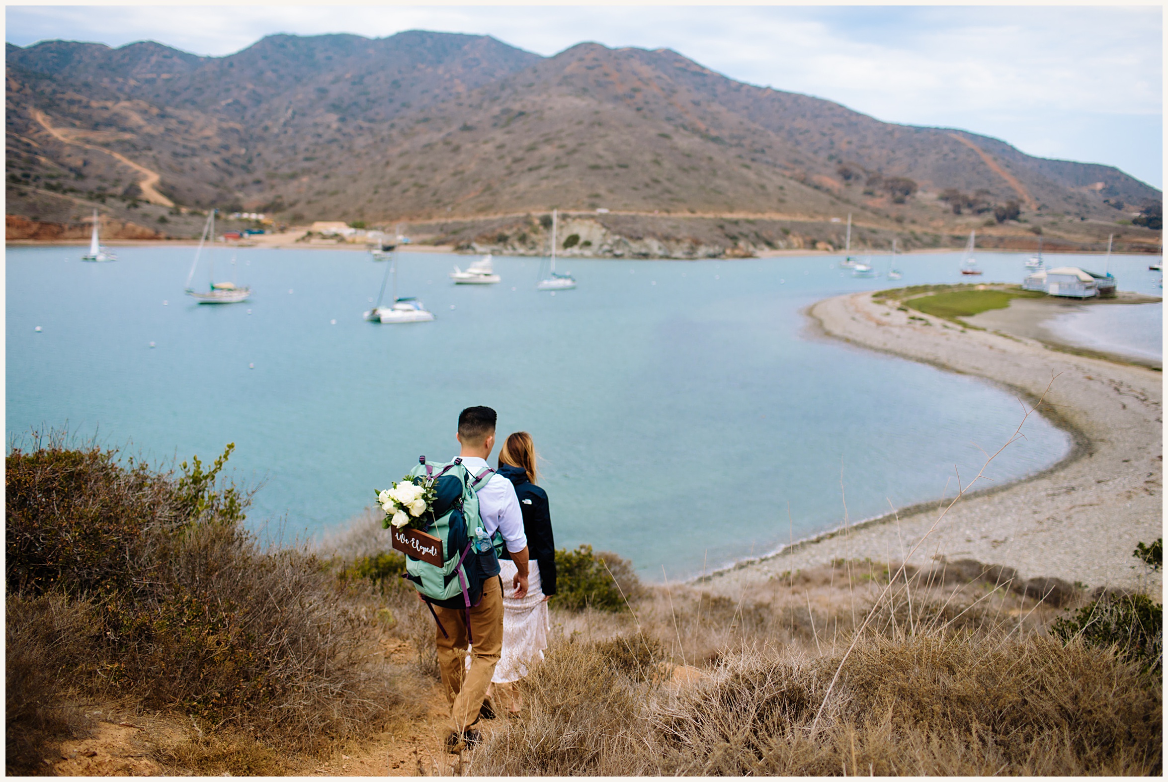 Photo of Bride and Groom hiking down Catalina Island trail near cove