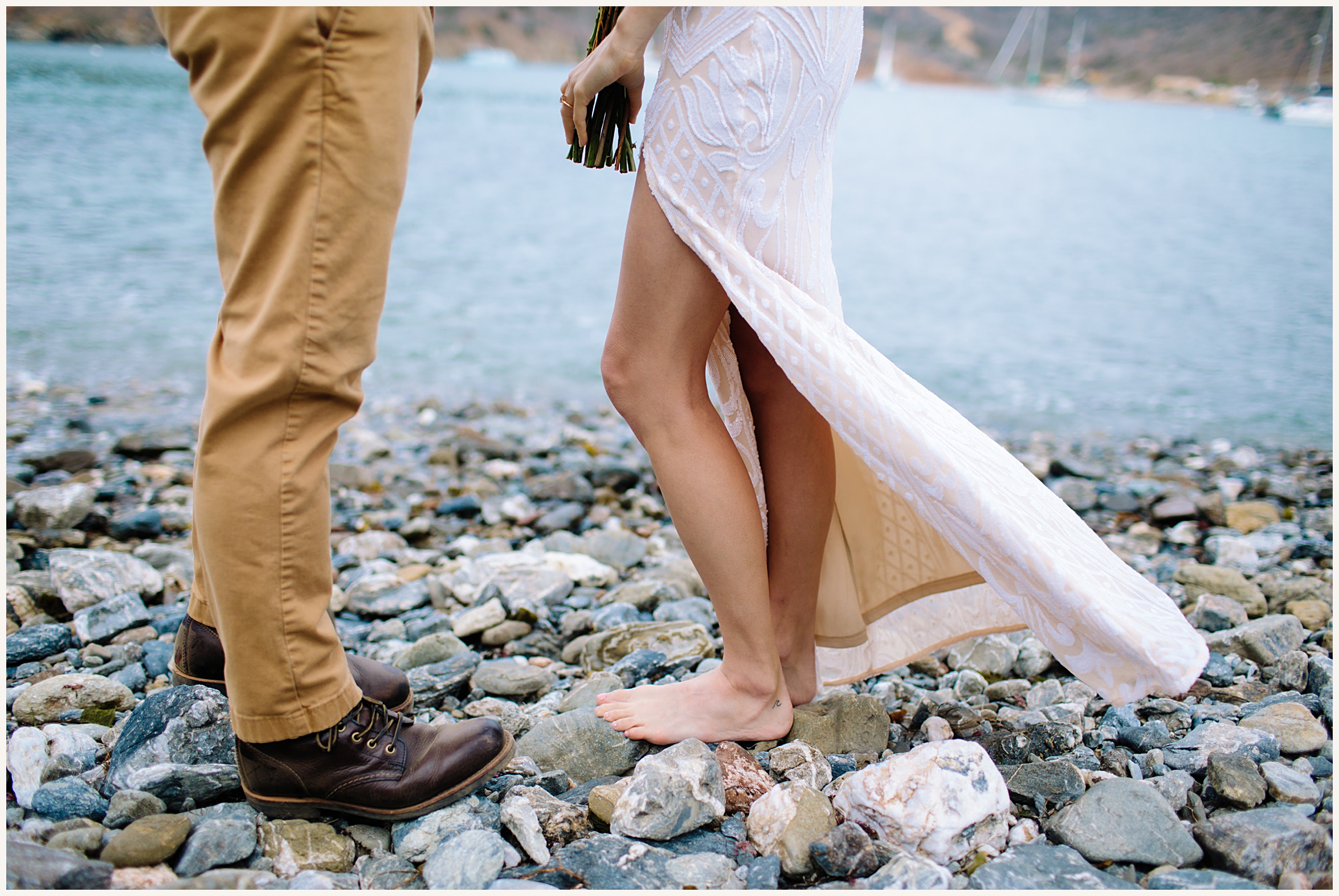 Photo of bride and groom on beach with bride barefoot on beach rocks