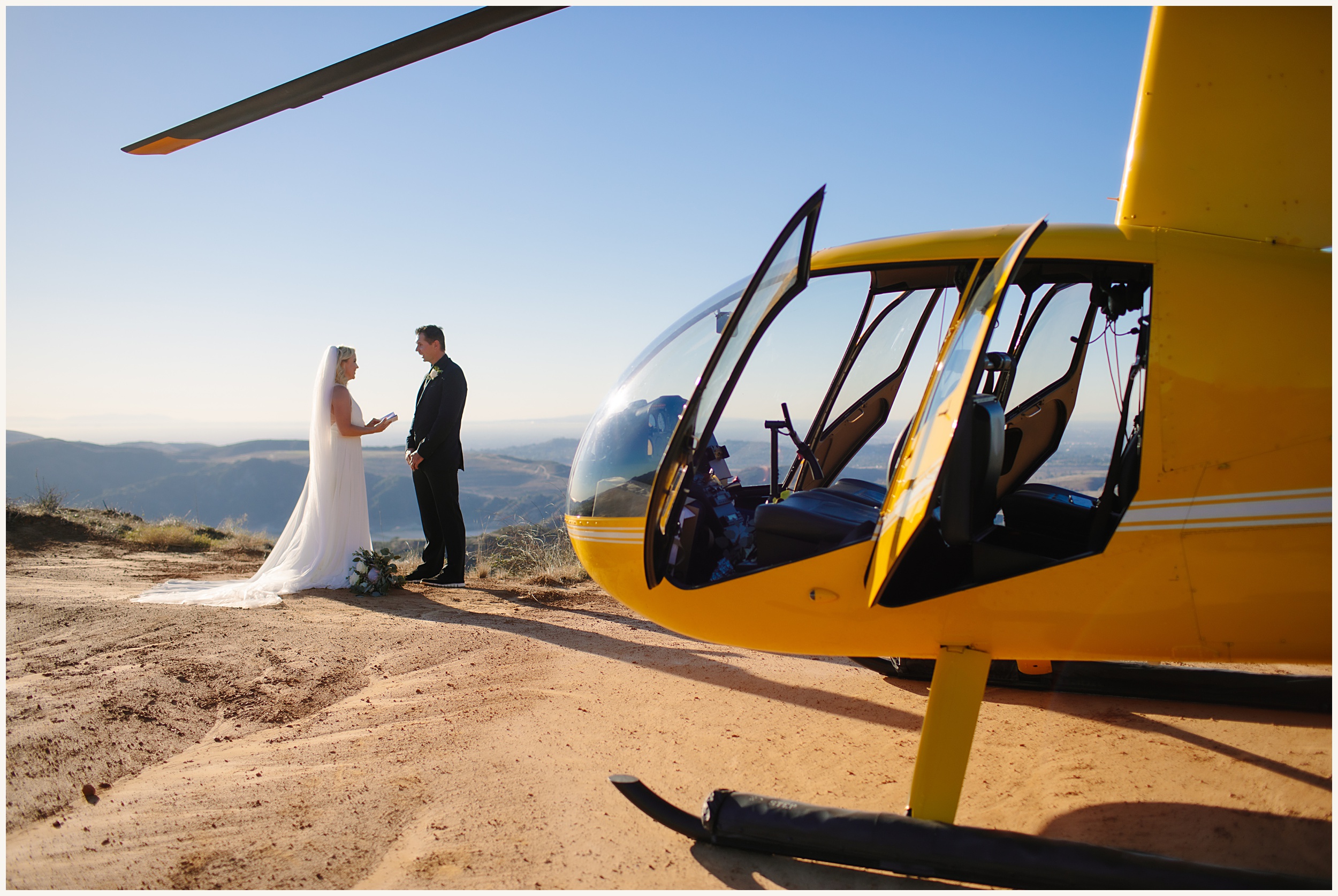Photo of bride and groom exchanging vows in front of yellow helicopter