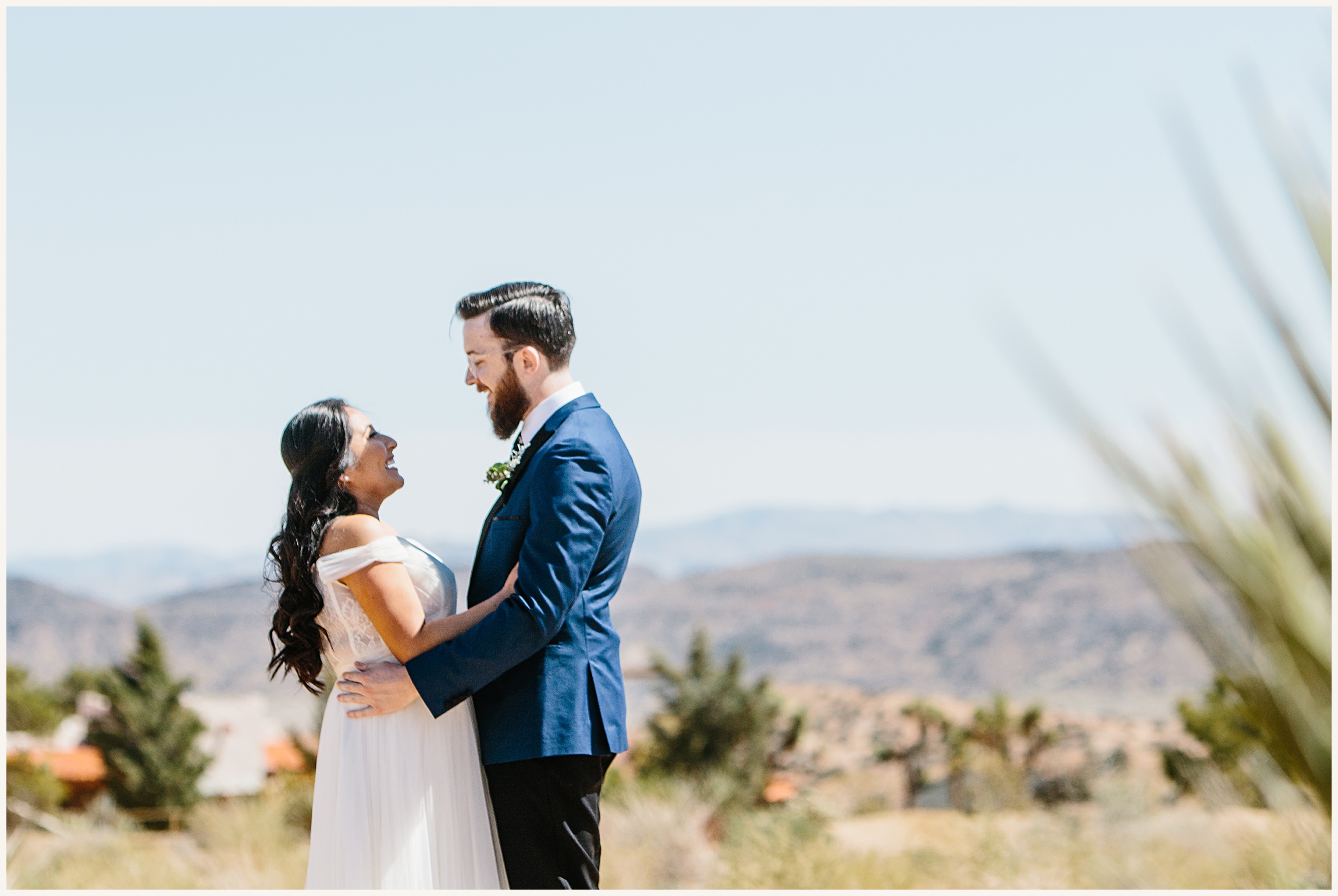 Photo of bride wearing off the shoulder white elopement dress and groom wearing a blue wedding suit