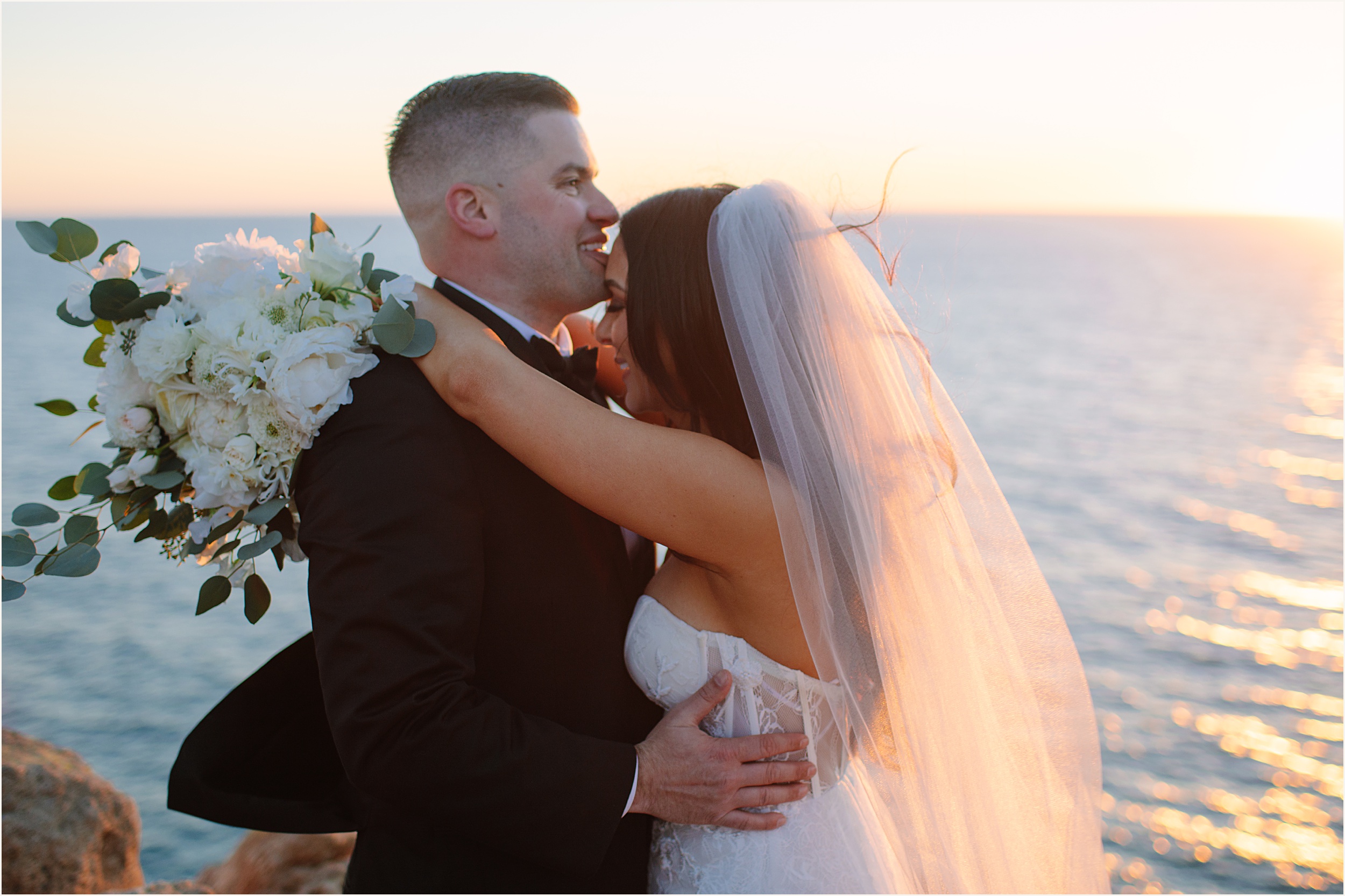 Photo of bride and groom holding eachother in front of sunset during their Malibu beach elopement