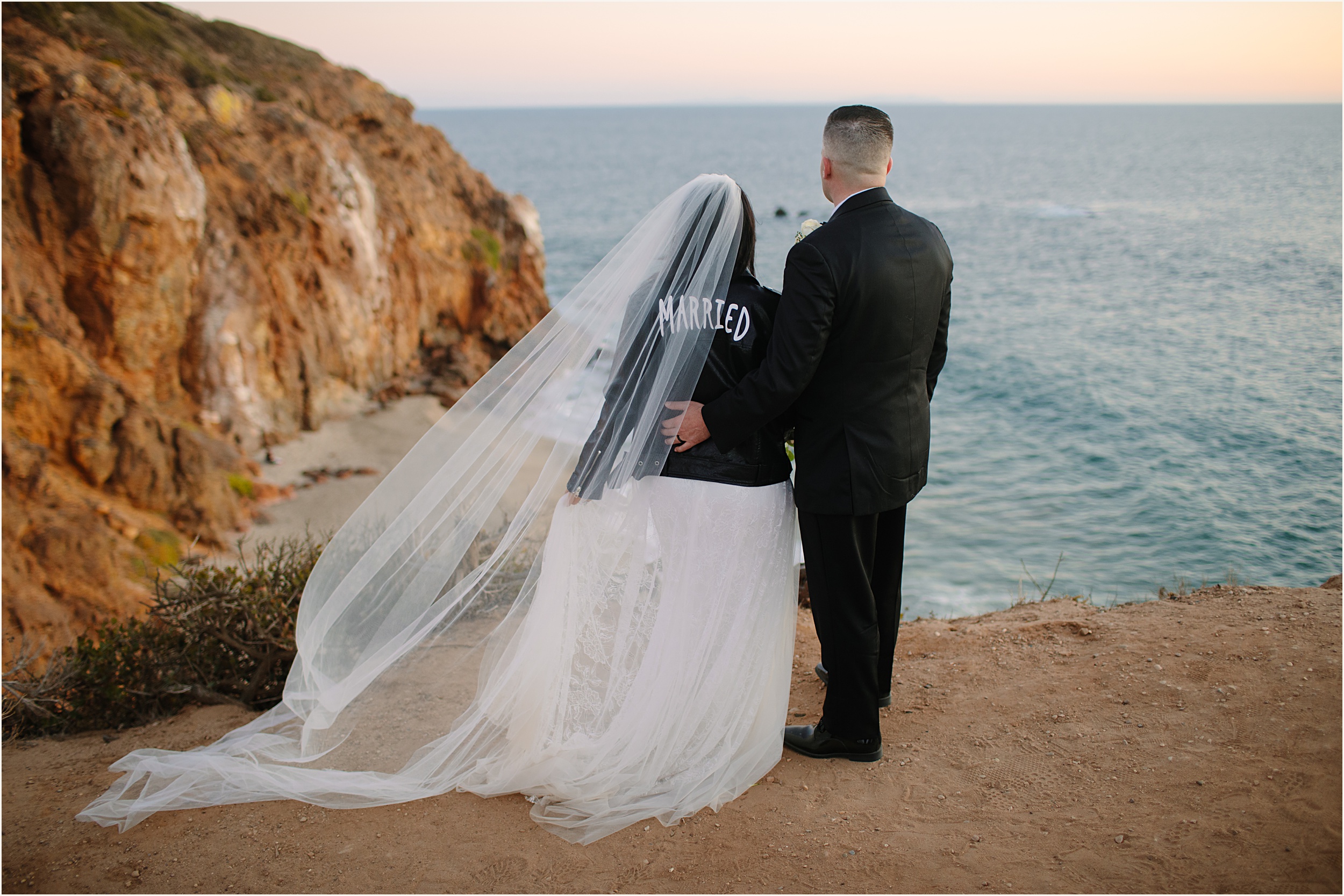 Photo of bride and groom looking out to cliffside view during sunset for their Malibu beach elopement