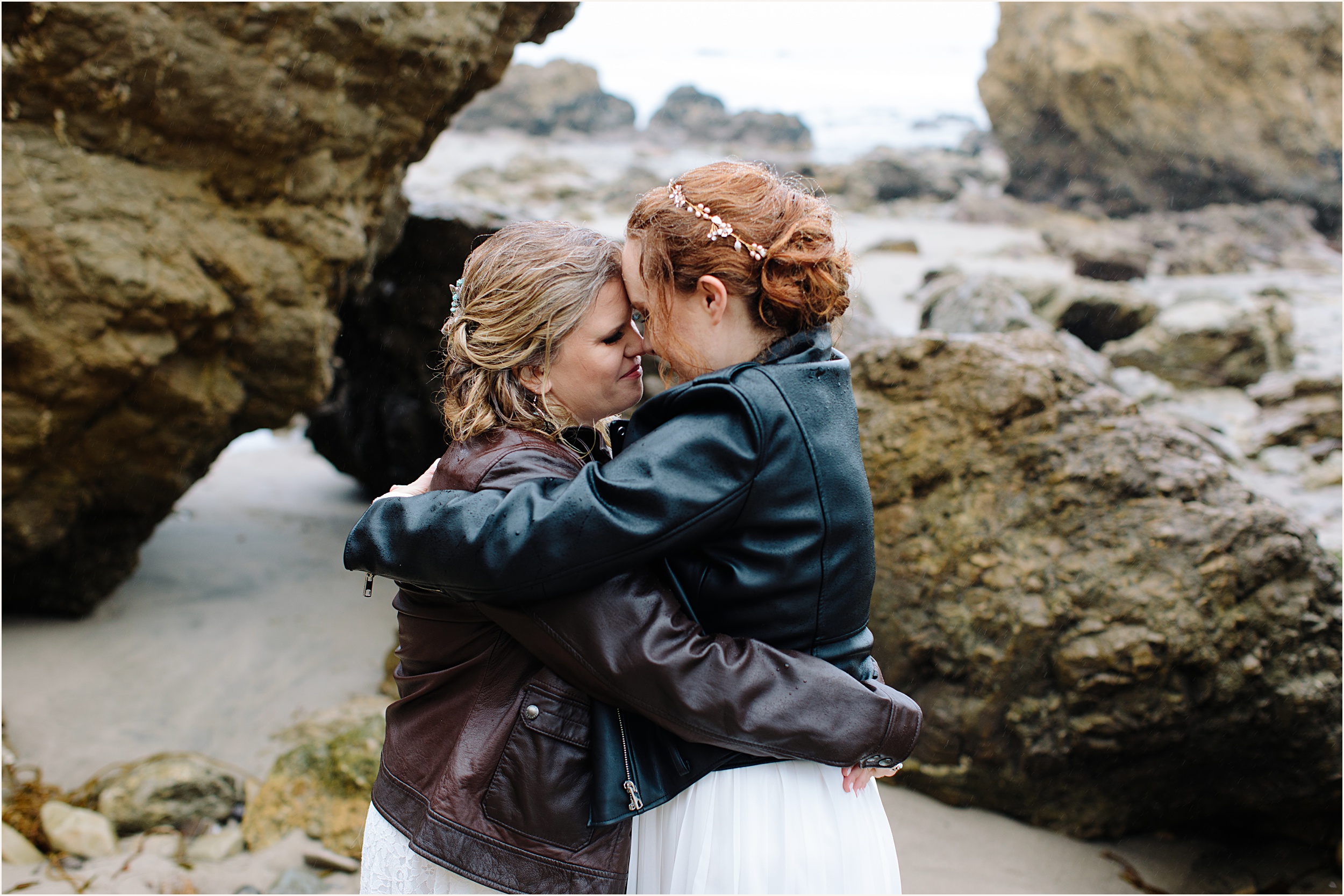 Photo of brides in leather jackets facing eachother hugging at El Matador beach